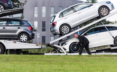 man loading cars in a truck for transport